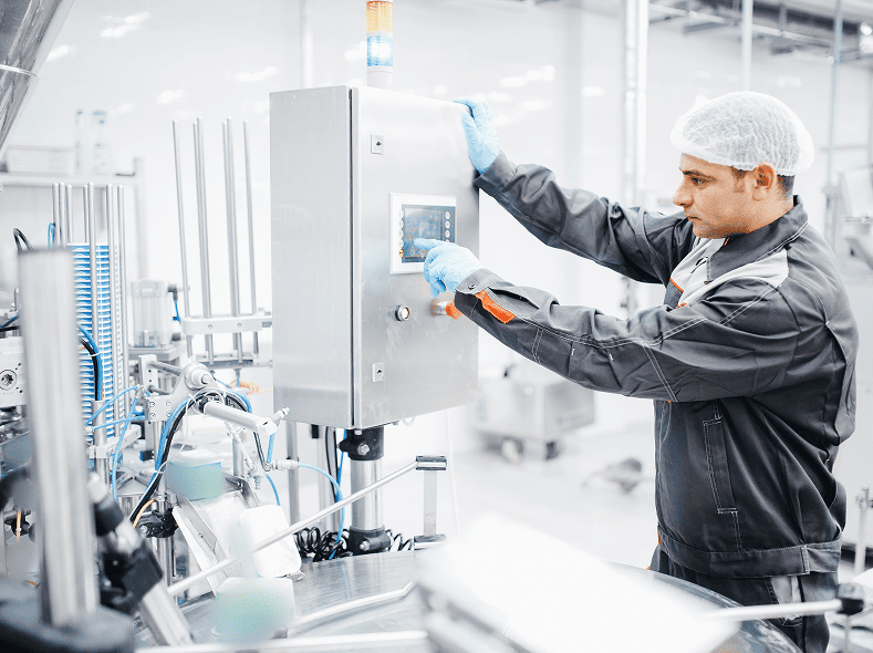 Technicien en tenue de protection contrôlant une machine de précision